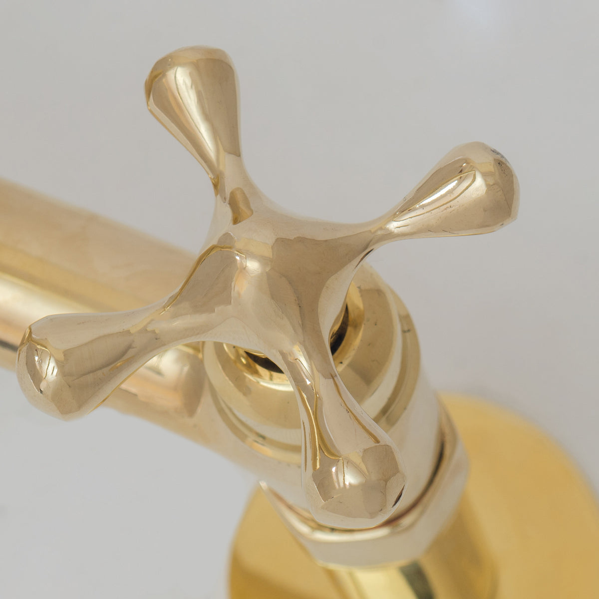 Simple cross handle detail on unlacquered brass bridge faucet