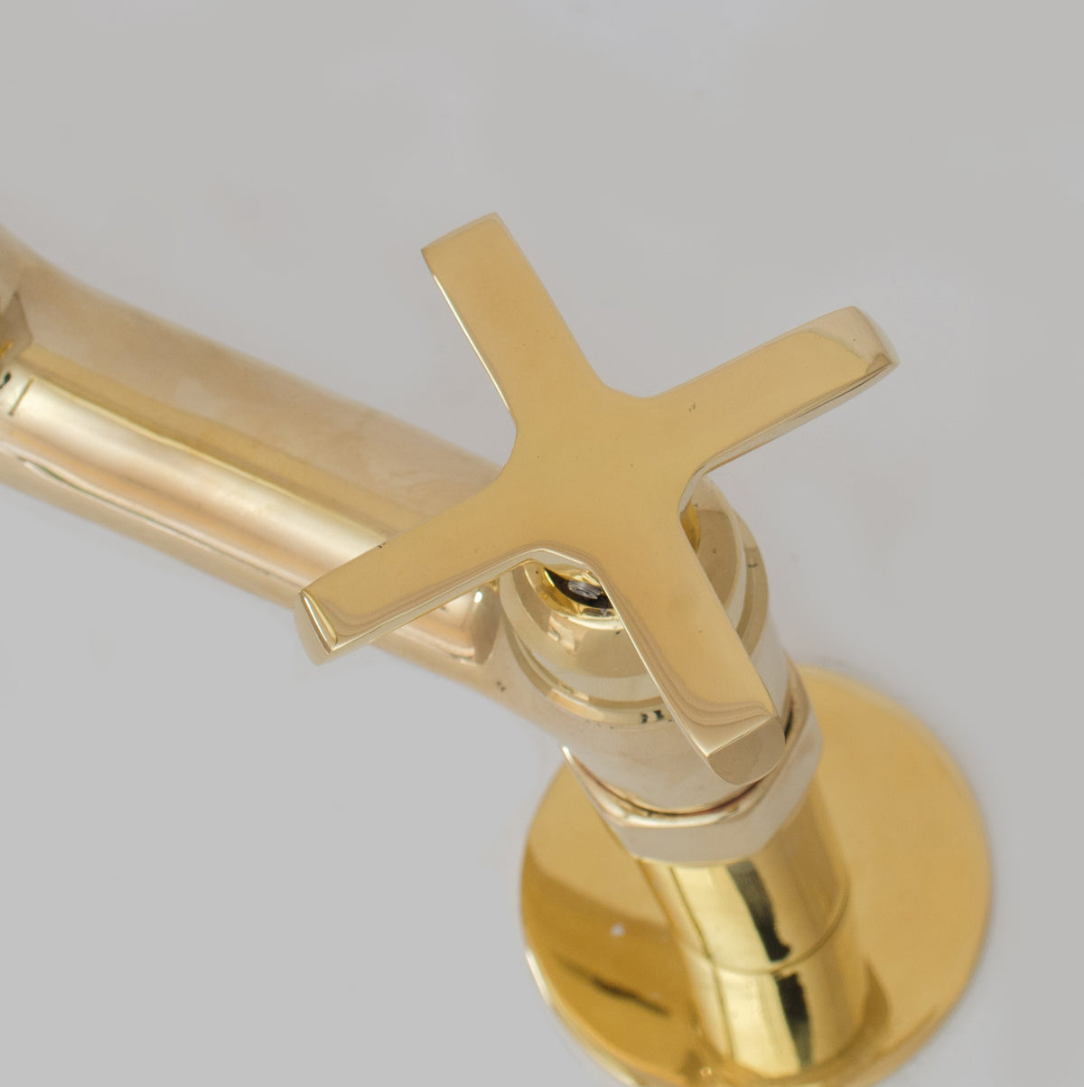 Flat cross handle detail on unlacquered brass bridge faucet